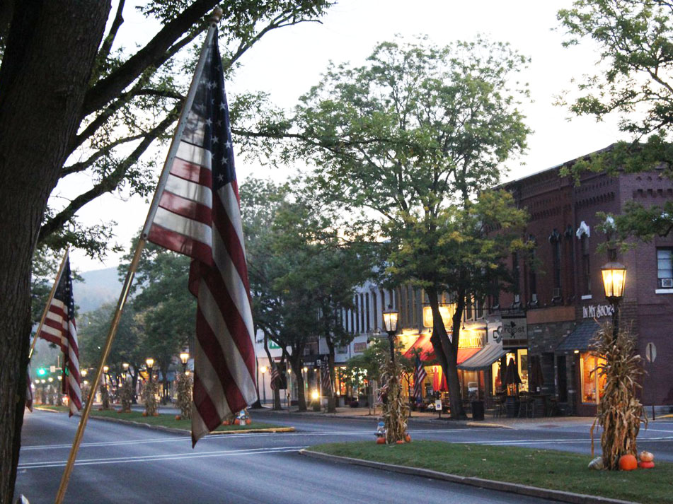 Street with street lights, autumn decor, and American flags
