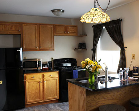 Kitchen with wooden cabinets and black appliances with a vase of yellow flowers on the island