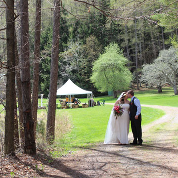 Bride and grooming kissing along a trail in the woods