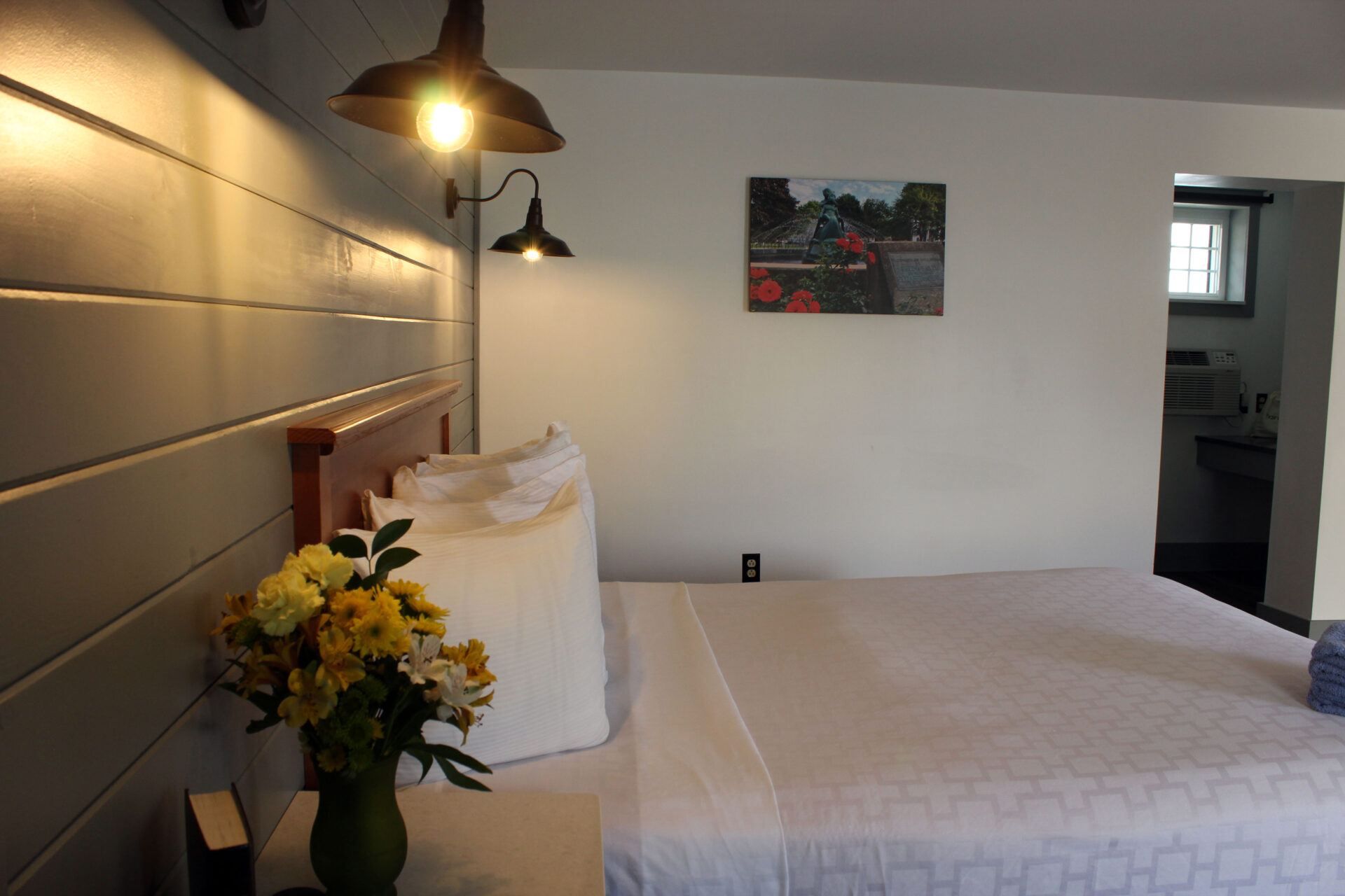 Bed made with white bed sheets with yellow flowers next to it