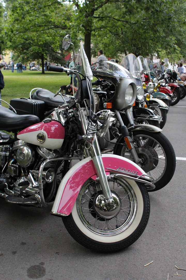 Line of motorcycles starting with a pink bike
