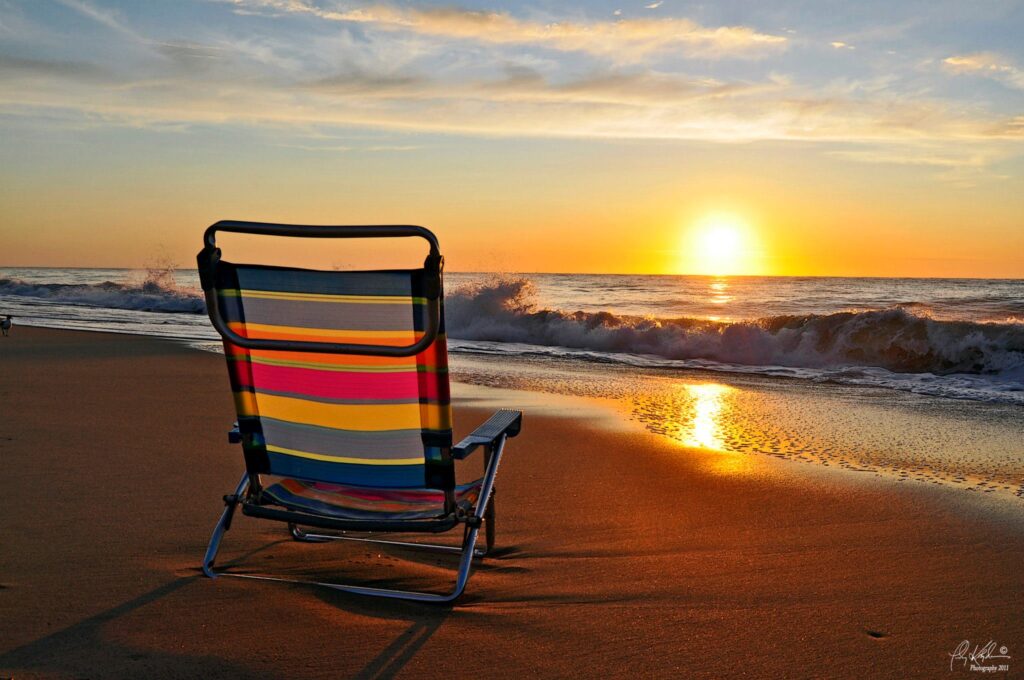 a chair sitting on the beach at sunset