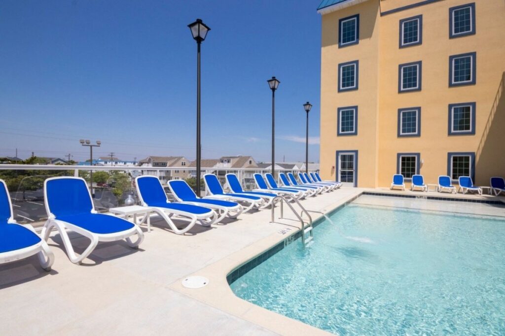 a row of blue lawn chairs next to a swimming pool