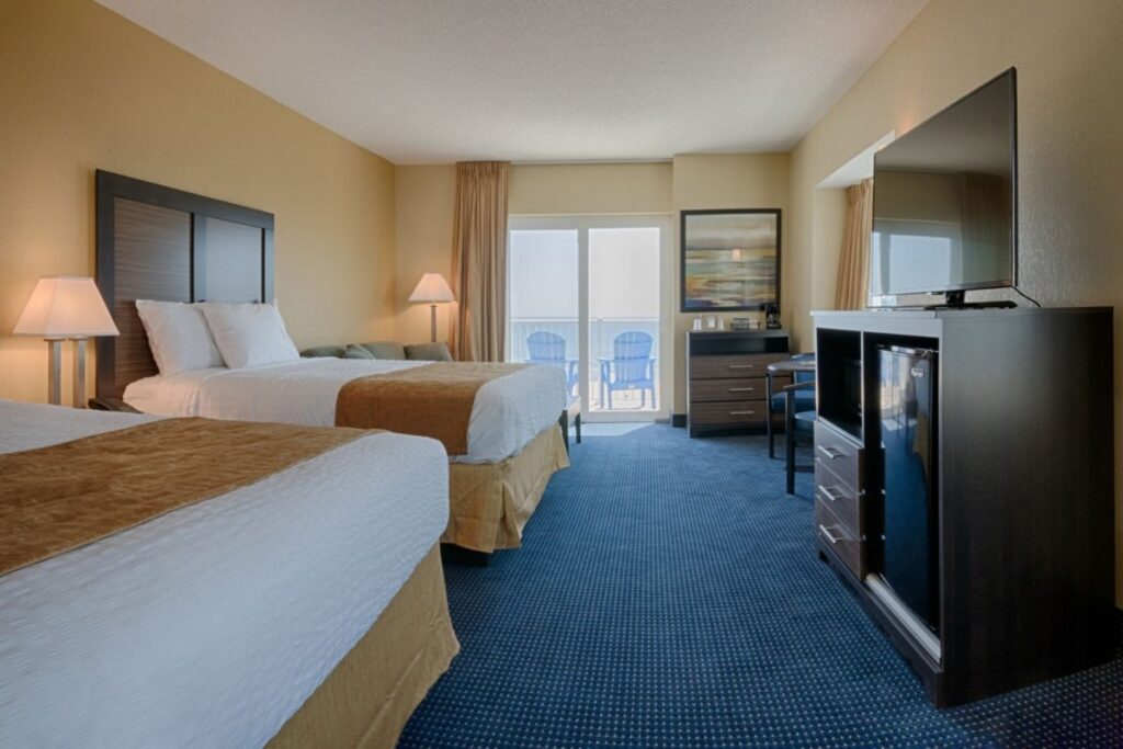 a hotel room with two beds and a flat screen tv