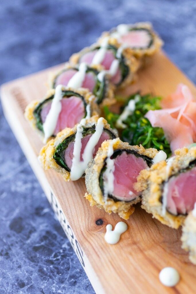 sushi rolls with sauce drizzled over them on a cutting board