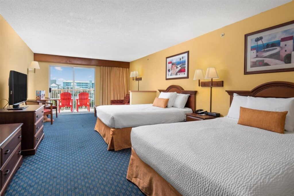 a hotel room with two beds and a flat screen tv
