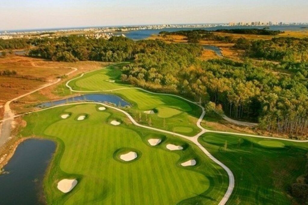 an aerial view of a golf course with water and trees