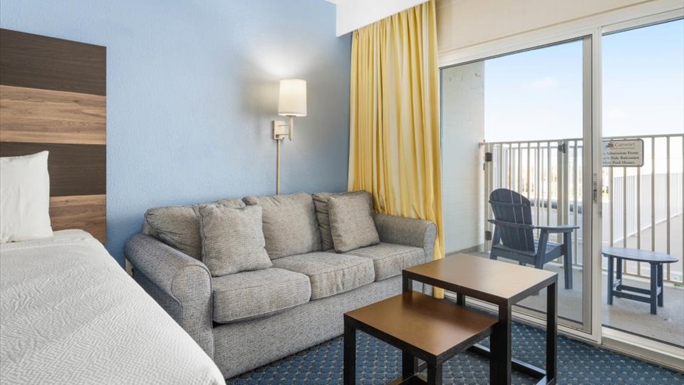 a hotel room with a couch, bed and balcony