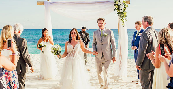 a newly married couple walking down the beach