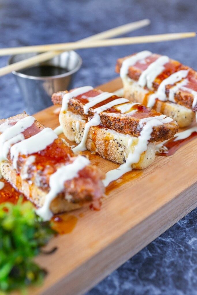 a wooden cutting board topped with meat covered in sauce
