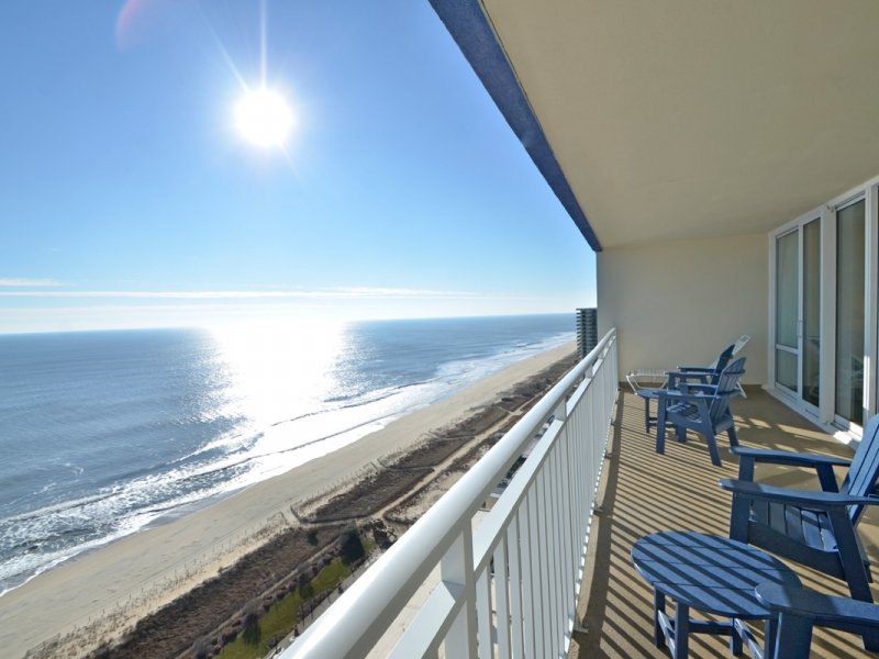 a balcony with blue chairs overlooking the ocean