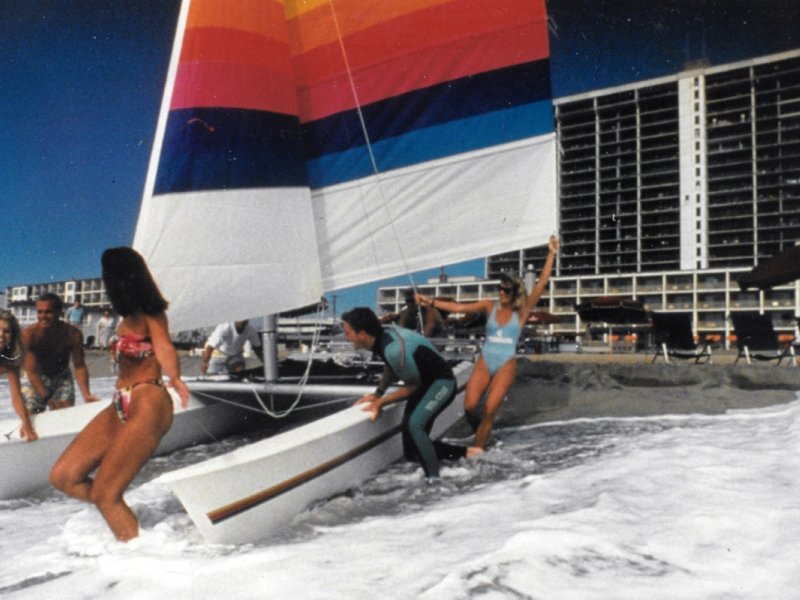 a group of people on a beach with a sailboat