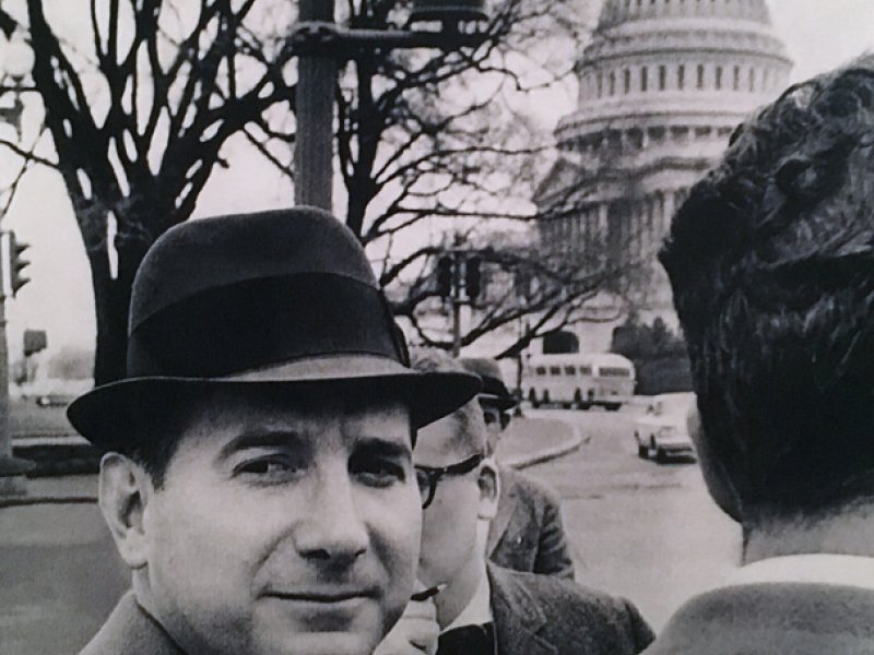a man in a hat and suit talking to another man