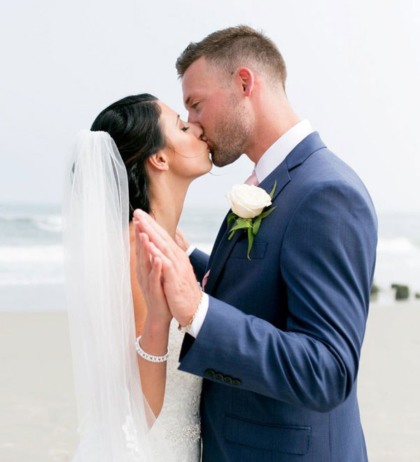 a bride and groom kissing on the beach
