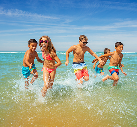 a group of children running into the ocean