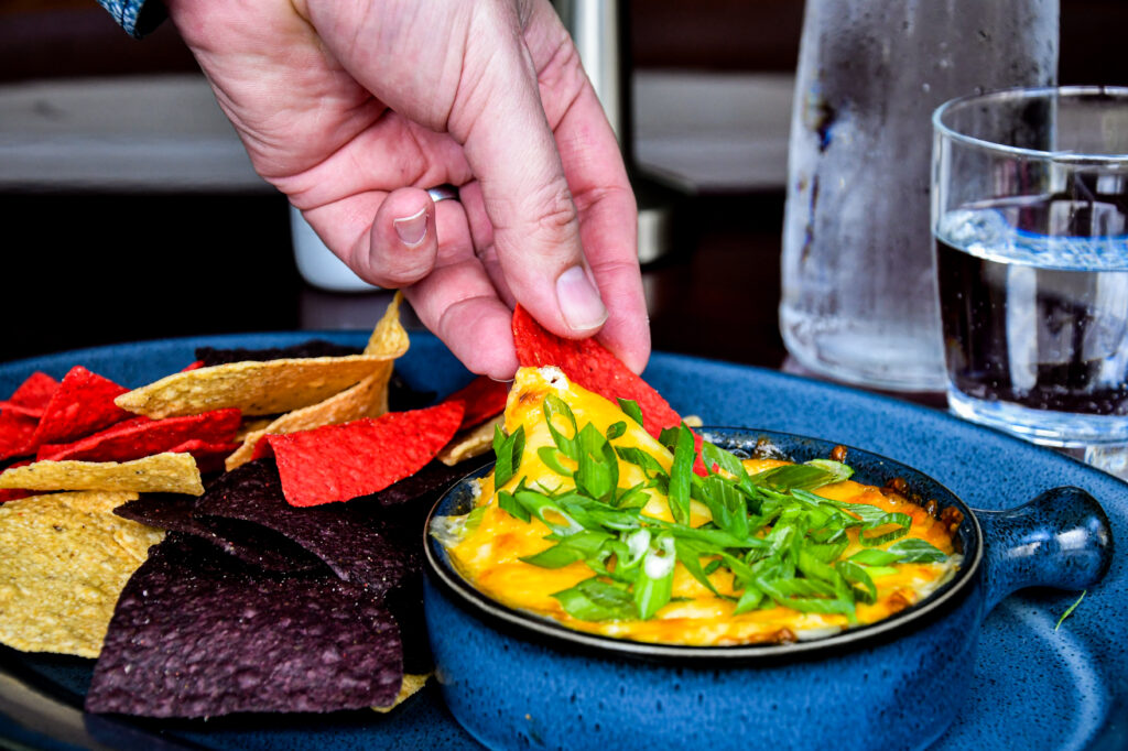 a person dipping a tortilla into a bowl of salsa