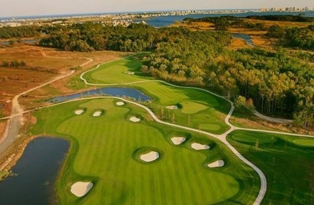 an aerial view of a golf course with water and trees