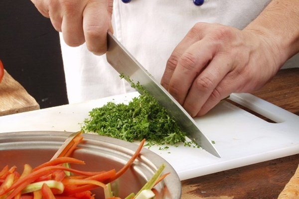 Greens being chopped up on a cutting board.