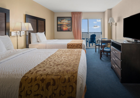 a hotel room with two beds and a flat screen tv