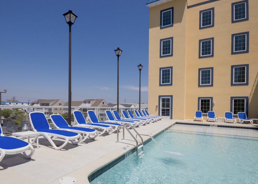 a row of lawn chairs next to a swimming pool
