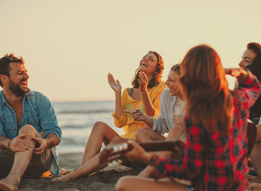 a group of people sitting on top of a sandy beach