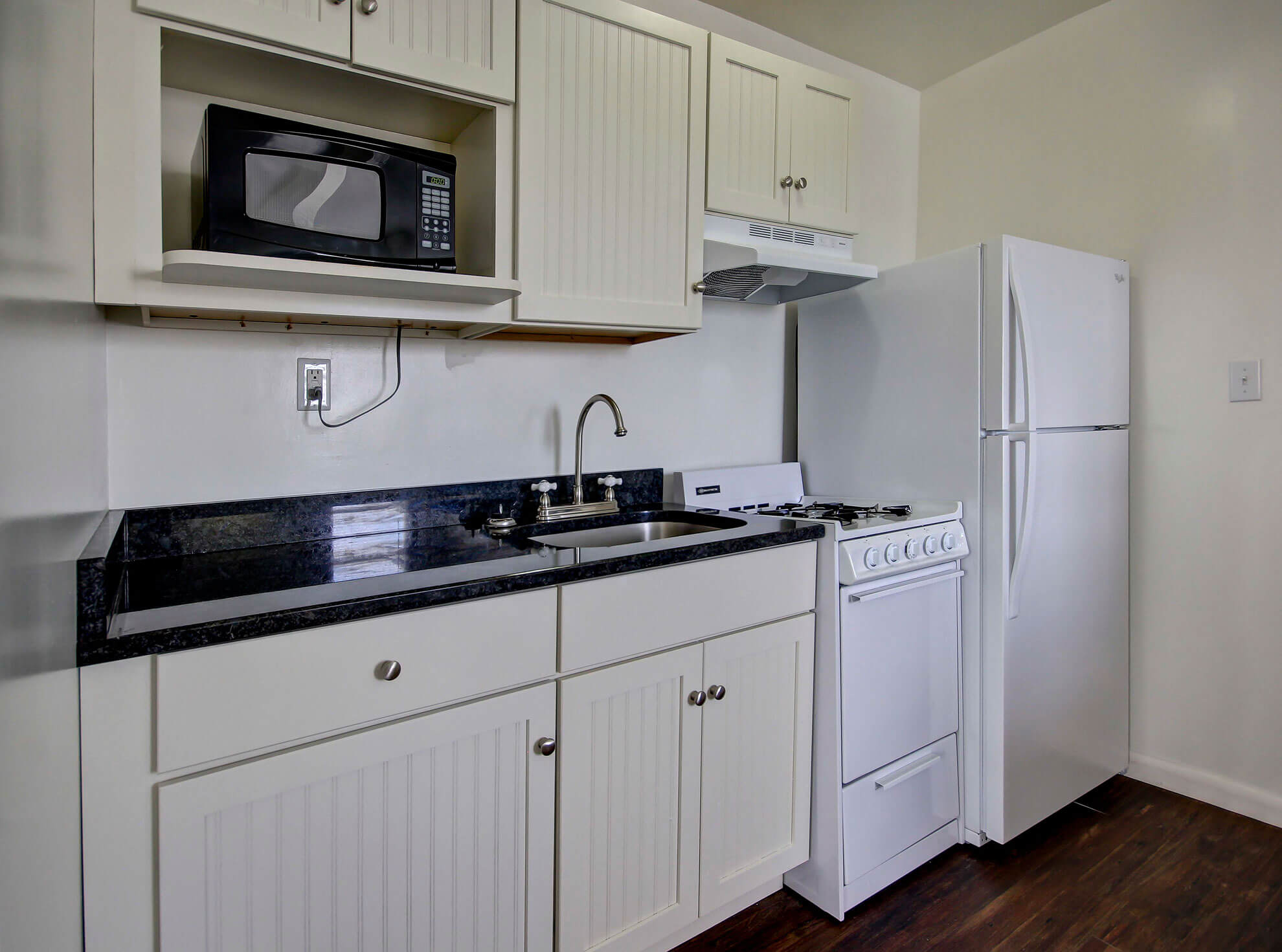 a kitchen with white cabinets and black counter tops