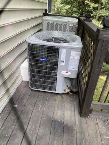 an air conditioner sitting on a porch next to a fence