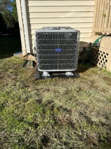 an air conditioner sitting in the grass next to a house