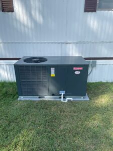 an air conditioner sitting in the grass next to a building