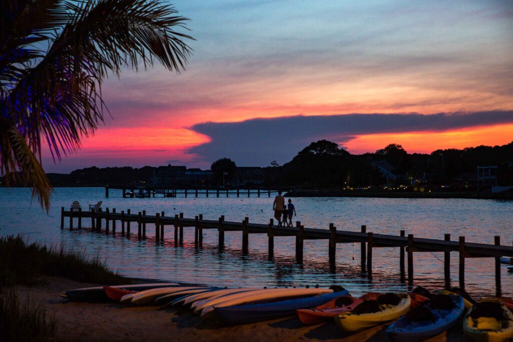 a group of kayaks sitting on top of a beach next to a pier