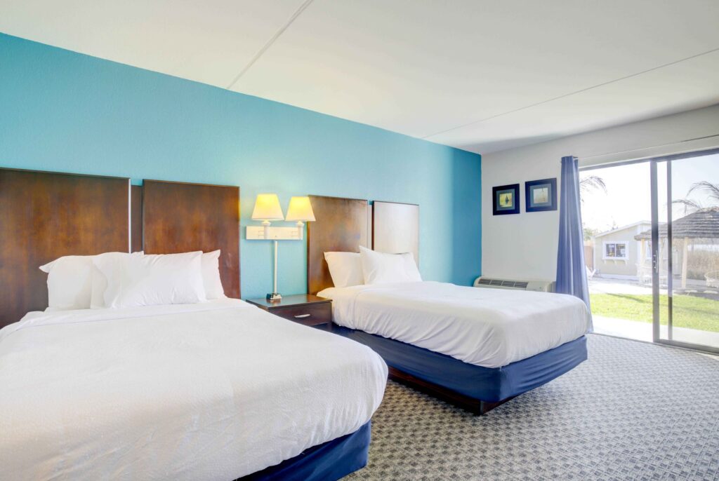 a hotel room with two beds and a sliding glass door