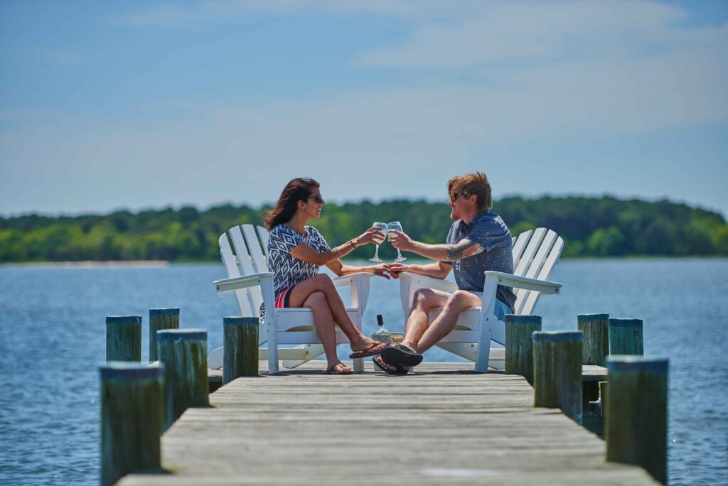 a couple of people sitting on top of a wooden dock