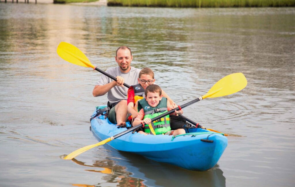 a man and two boys in a blue kayak