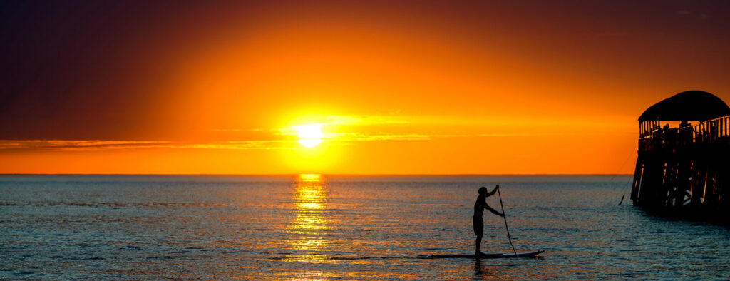 a person on a surfboard in the water at sunset