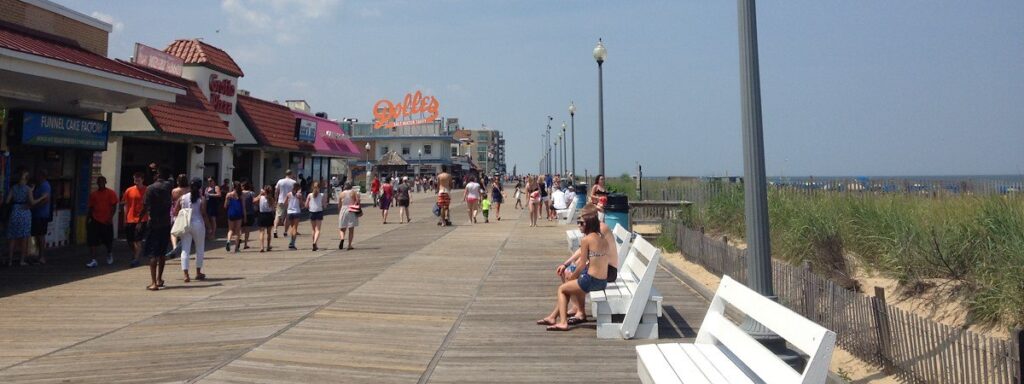 a crowd of people walking along a boardwalk next to a beach