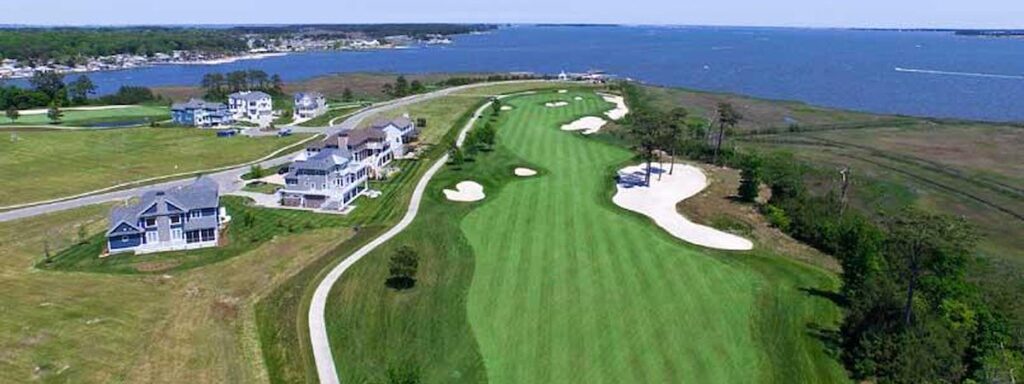 an aerial view of a golf course near a body of water