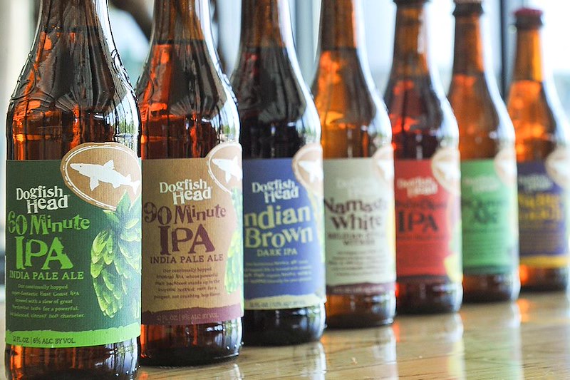 a row of beer bottles sitting on top of a wooden table