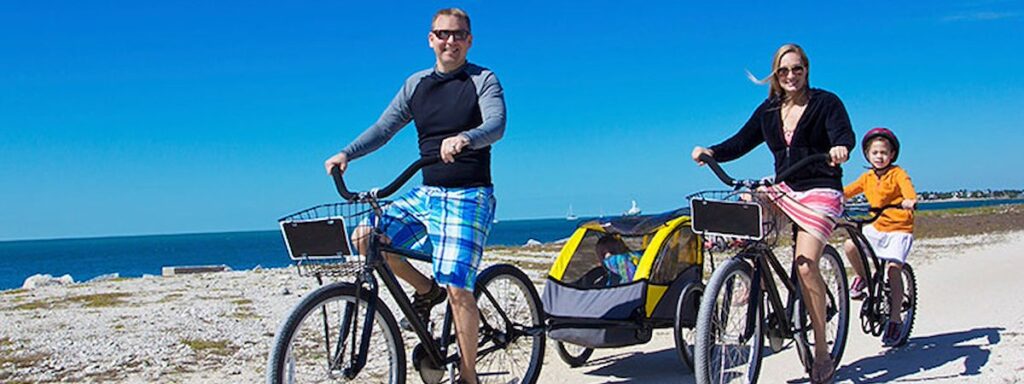 a man, woman and child riding bikes on the beach