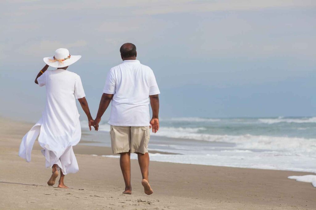 a man and woman walking on the beach holding hands