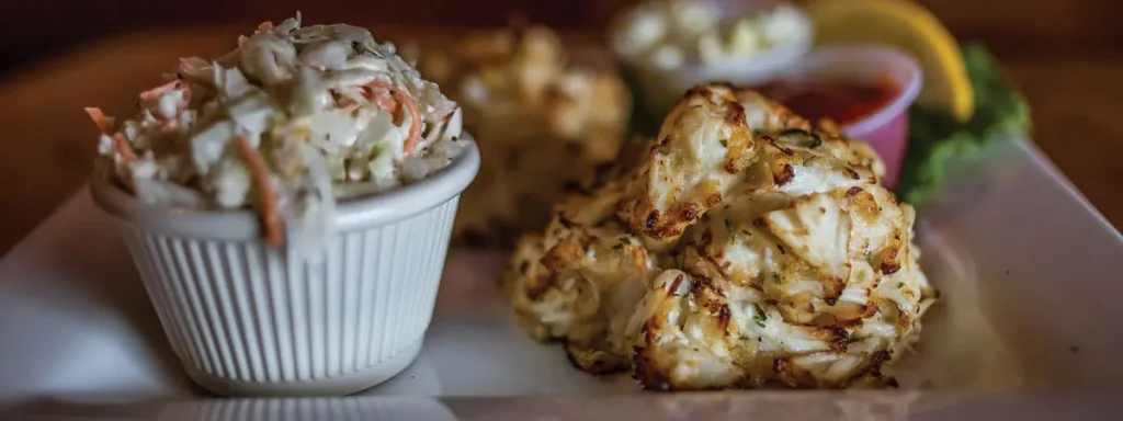 Crab cakes and coleslaw on a plate.