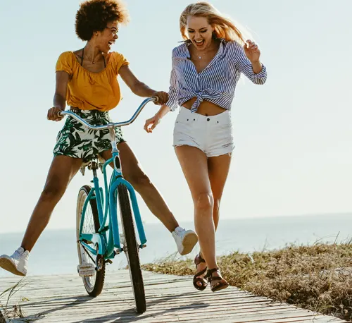 A girl on a bike and another girl running next to her