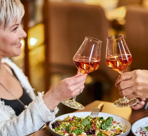 A couple toasting their wine glasses together