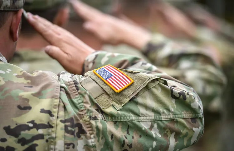 Military men saluting the American Flag