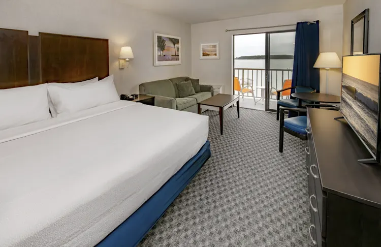 A king size bed in a hotel room over looking the bay.