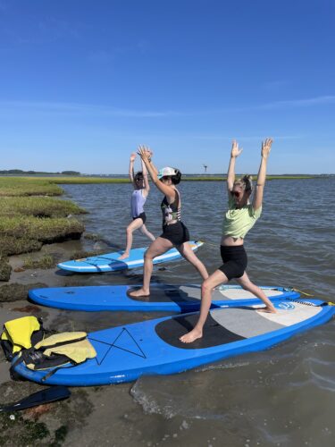 people doing yoga on a paddle board