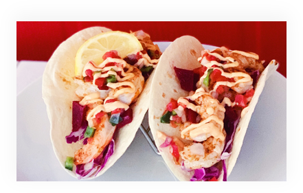 Two shrimp tacos with toppings and sauce