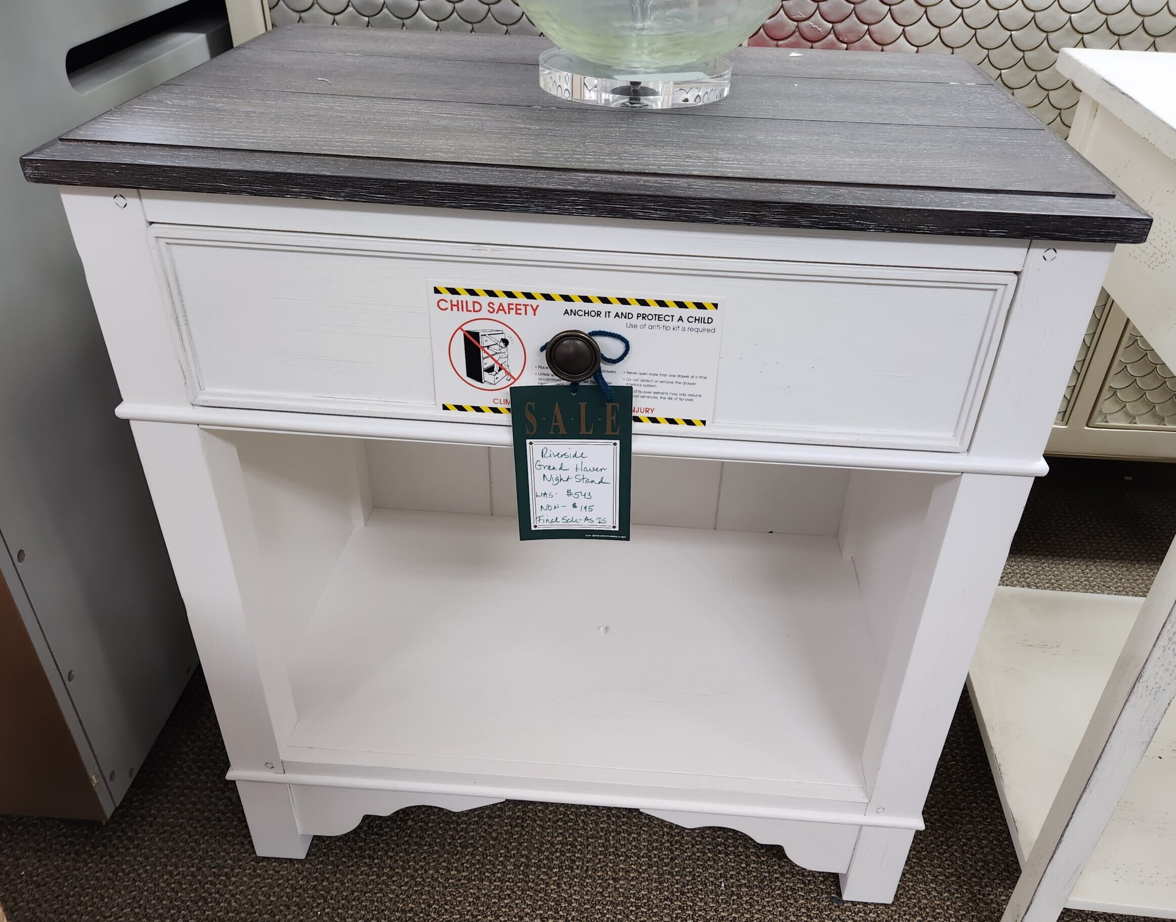 a small white cabinet with a glass vase on top