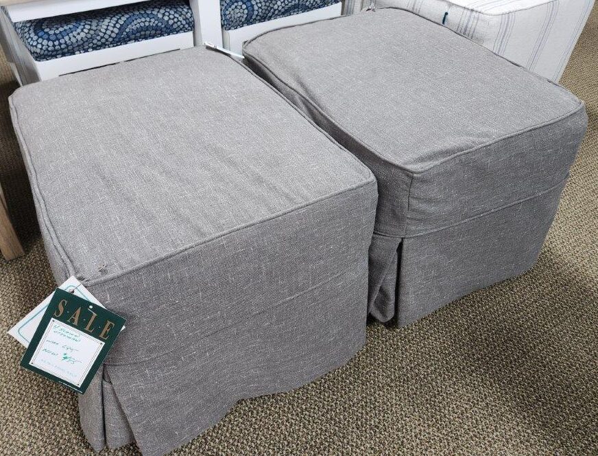 two gray chairs with matching footstools in a store