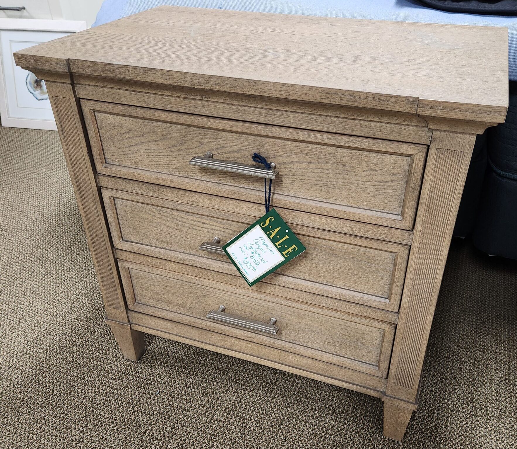 a wooden cabinet with a label on it next to a bed