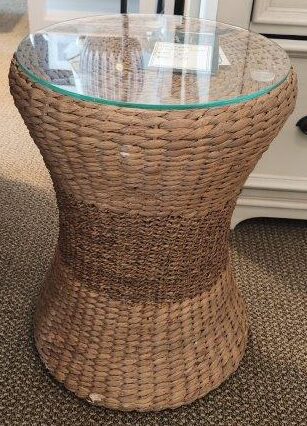 a wicker side table with a glass top